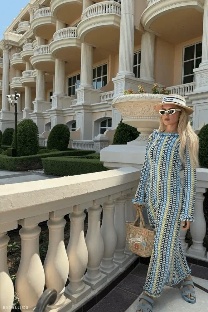 Elegant woman in a patterned 'Berna' maxi dress stands near a grand building, showcasing a timeless and versatile style.