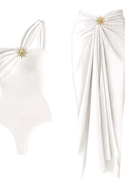 Elegance Beach Set with asymmetrical swimsuit and wrap skirt, featuring gold embellishment for a glamorous look.