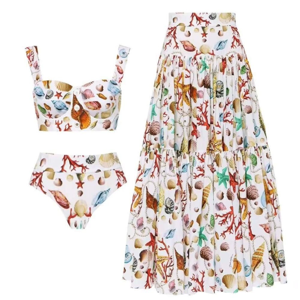 Seaside Elegance Set featuring a shell and coral pattern with a bustier top, high-waist bikini, and flowing skirt.
