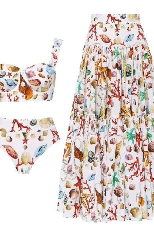 Seaside Elegance Set featuring a shell and coral pattern with a bustier top, high-waist bikini, and flowing skirt.