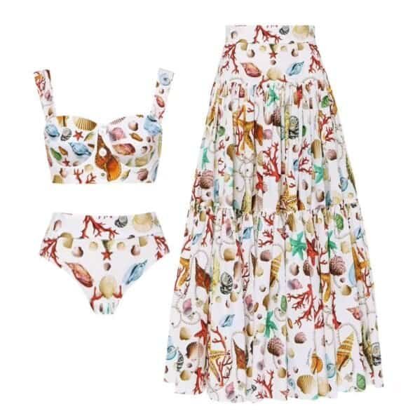 Seaside Elegance Set featuring a shell and coral pattern with a bustier top, high-waist bikini, and flowing skirt.